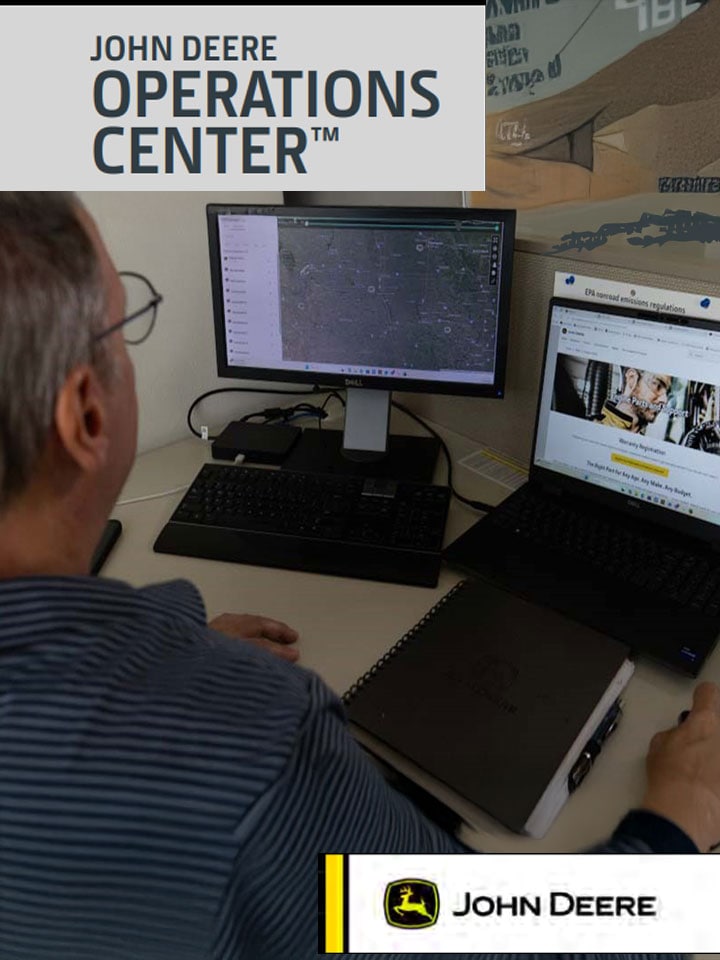 Person using John Deere Operations Center on dual computer monitors displaying map and compliance data.
