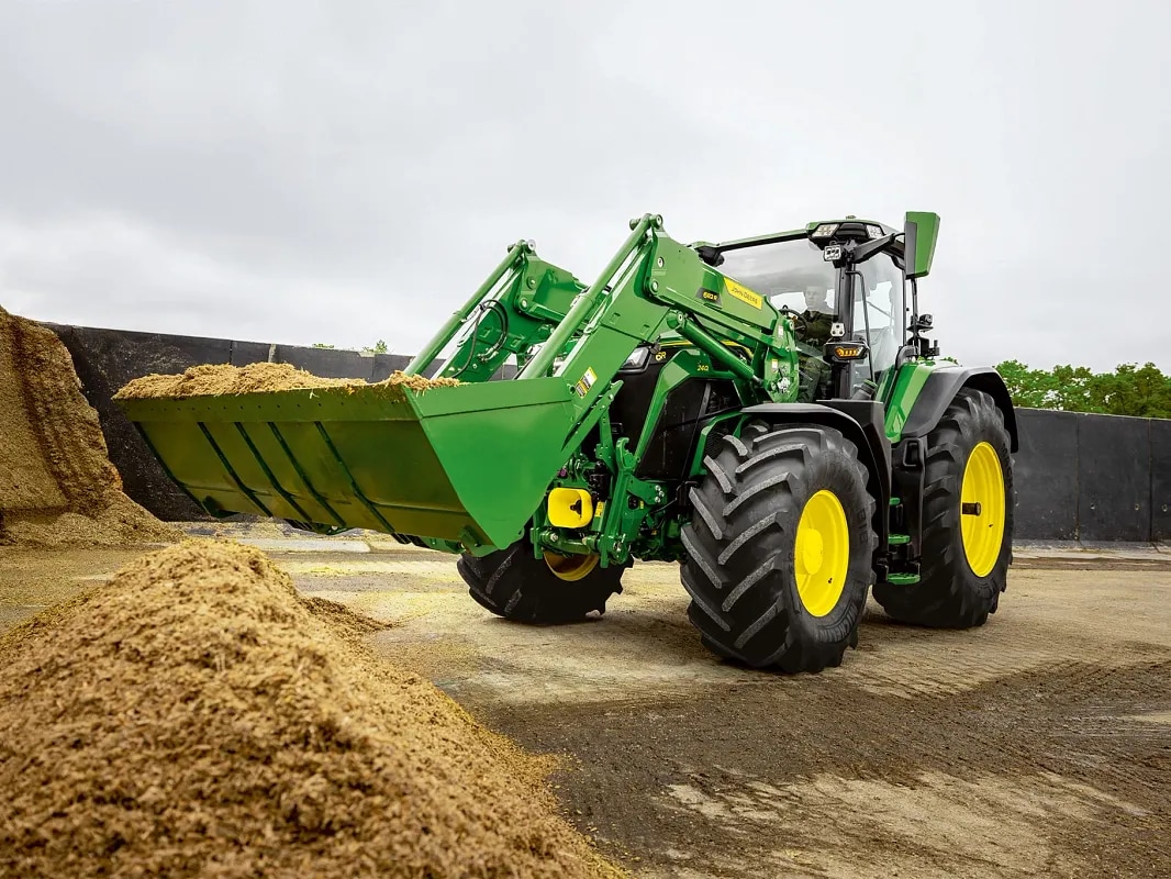 John Deere -traktorin säilörehulla täytetty etukuormaimen kauha materiaalin käsittelyn aikana.