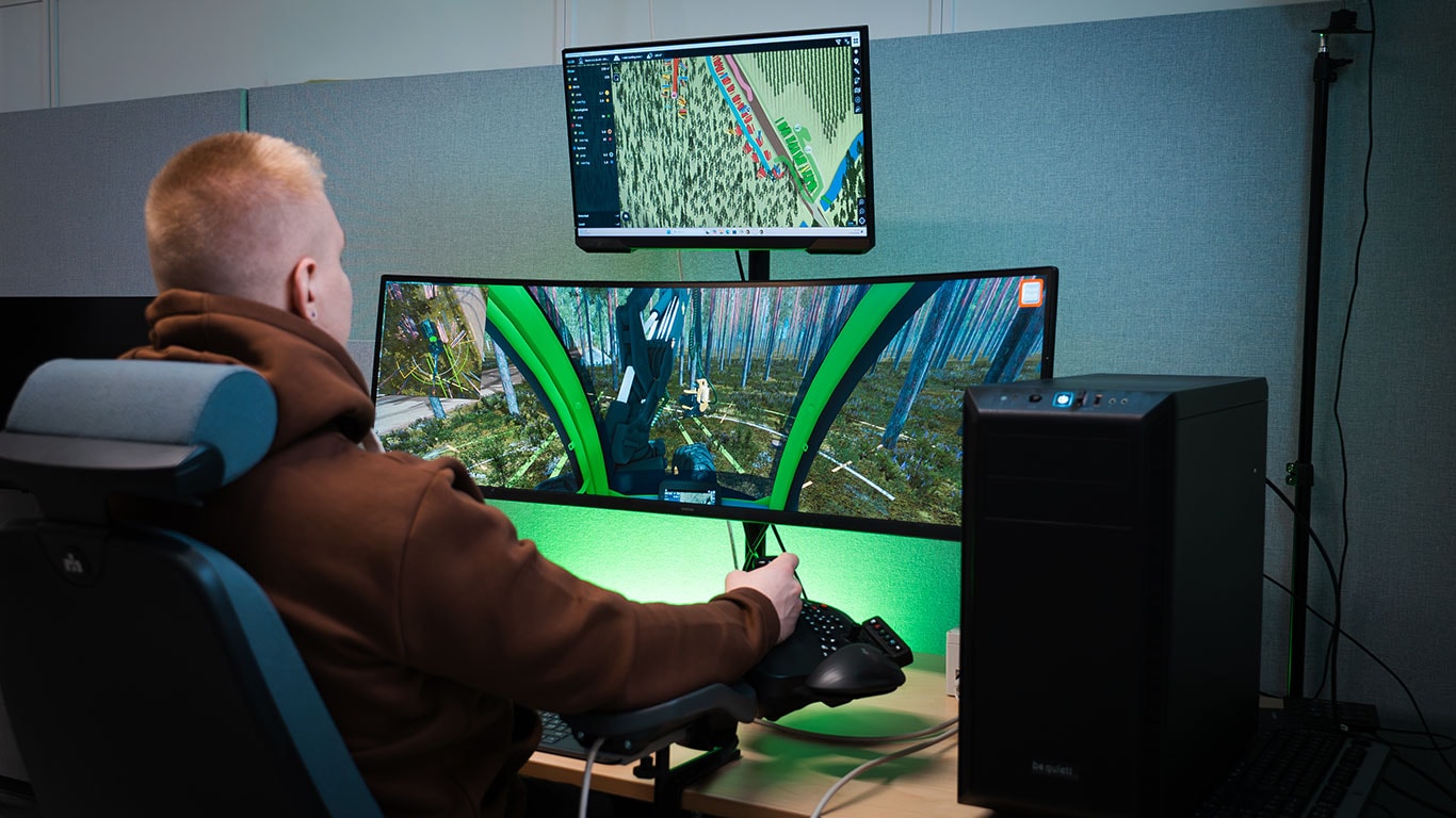 Metsäkoneen kuljettaja käyttämässä John Deere Simulator Edu -simulaattoria