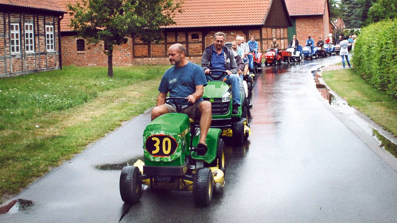 Vanha ajettava ruohonleikkuri, kodinomistaja, kylä, paraati