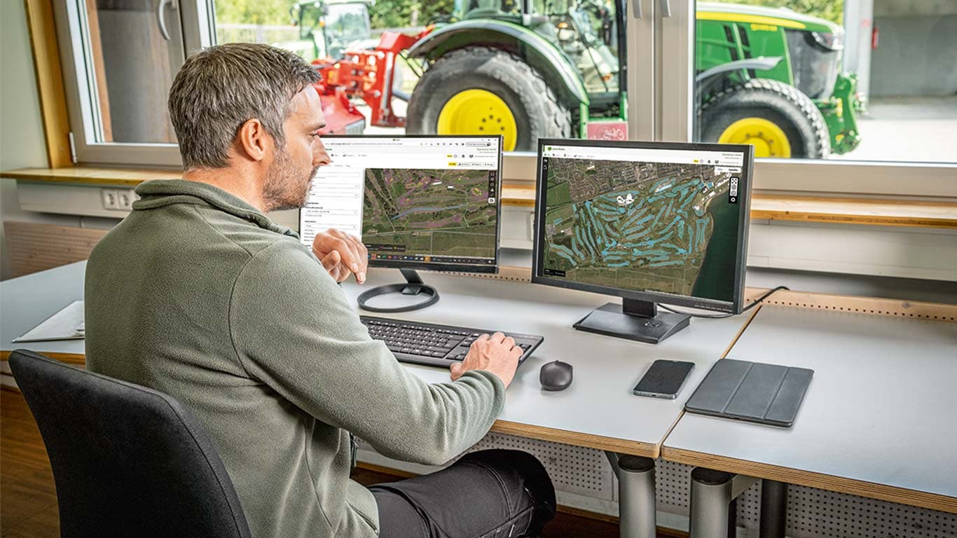 Vastaava golfkentänhoitaja tarkastelee golfkentän karttoja tietokoneellaan.