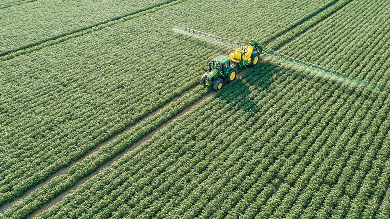 John Deere 6M-sarjan traktori vet&auml;&auml; hinattavaa M700-ruiskutuslaitetta perunapellolla