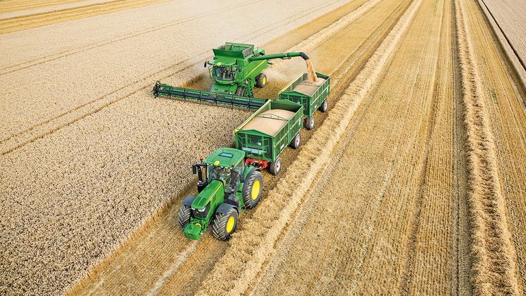 John Deere S-sarjan leikkuupuimuri tyhjent&auml;&auml; vehn&auml;&auml; kahteen traktorin vet&auml;m&auml;&auml;n per&auml;vaunuun