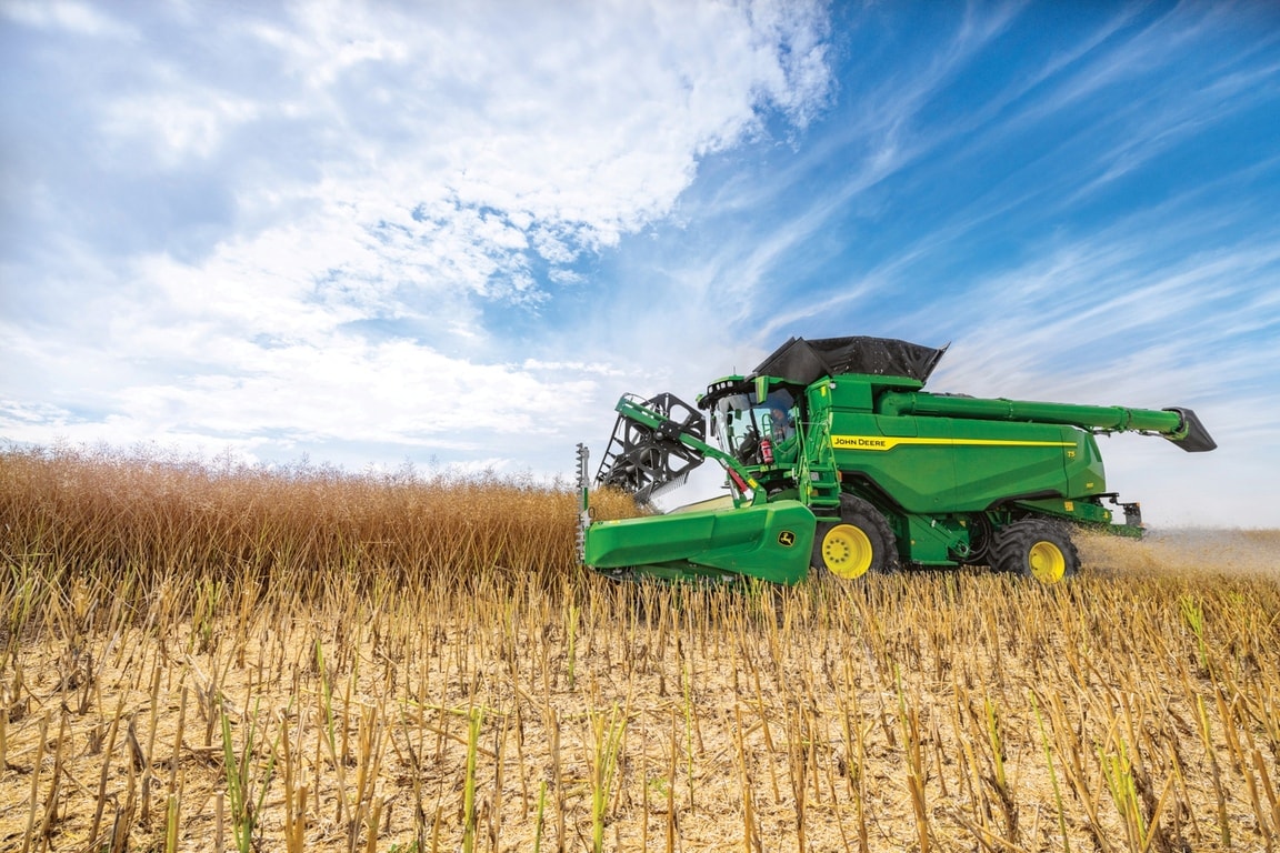 John Deere -leikkuupuimuri korjaa satoa leikkuupöydällä sinisen taivaan alla sadonkorjuun aikana