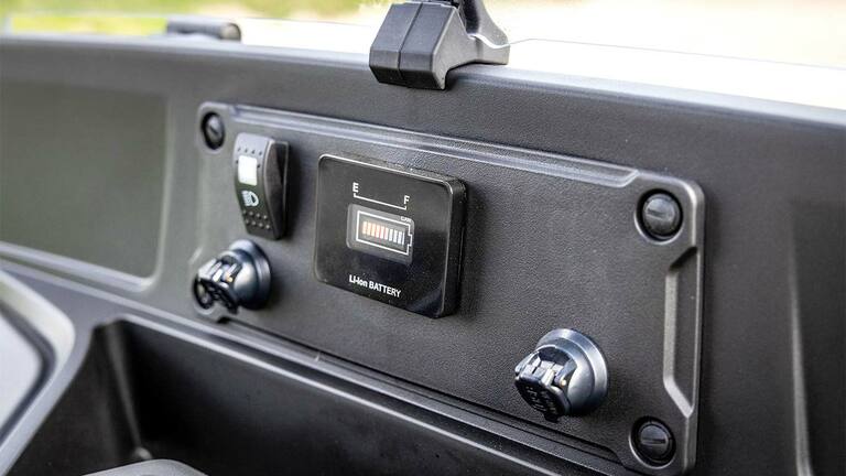 John Deere Gator GS -sähkömallin kojetaulu, jossa näkyy akun varaustilan ilmaisin ja verkkoliitännät.