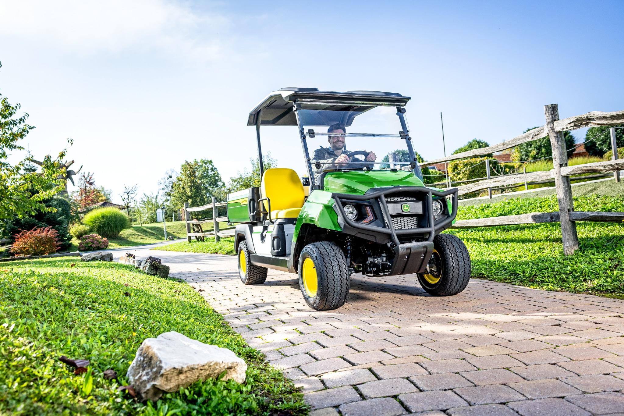 Gator GS -lava-ajoneuvo ajamassa päällystetyllä tiellä maisemoidulla alueella Gator GS -lava-ajoneuvo ajamassa päällystetyllä tiellä maisemoidulla alueella